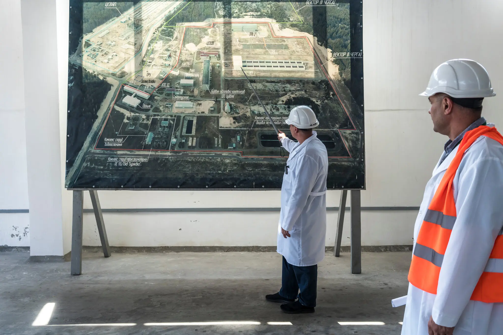 Робітник із фотографією місця аварії на Чорнобильській АЕС минулого літа. Екран призначений для безпечного розбирання пошкодженого реактора під ним.